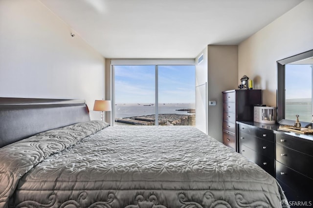 bedroom featuring a water view and expansive windows