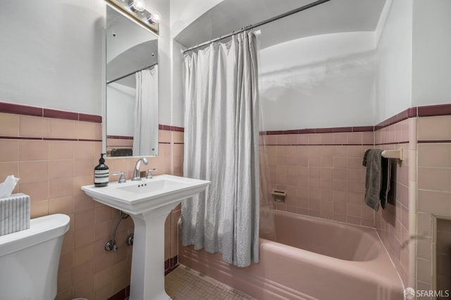 full bathroom featuring shower / bath combo, sink, tile walls, and toilet