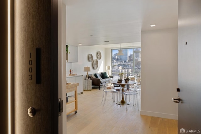 hall with baseboards and light wood finished floors