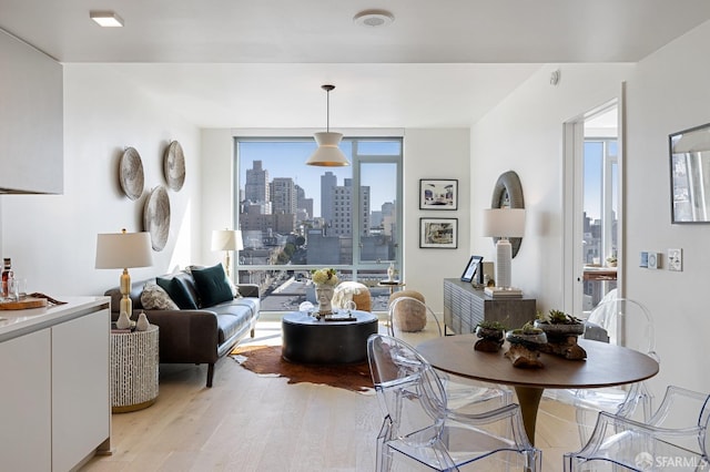 dining room featuring light wood-type flooring, a view of city, and floor to ceiling windows