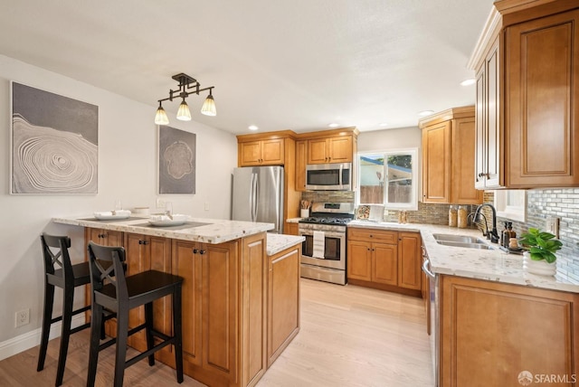 4649 Theta St, Fremont, CA 94536 - kitchen featuring appliances with stainless steel finishes, light wood-style flooring, tasteful backsplash, light stone countertops, and a kitchen bar
