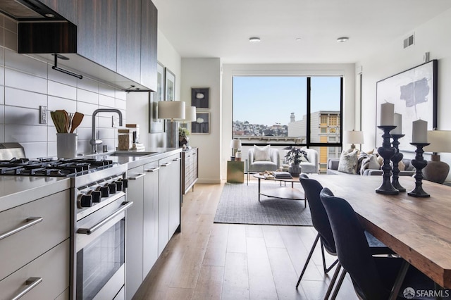 1188 Valencia St Unit 403, San Francisco, CA 94110 - kitchen with modern cabinets, high end stainless steel range, light wood finished floors, and extractor fan