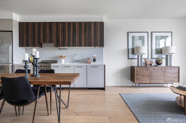 1188 Valencia St Unit 403, San Francisco, CA 94110 - kitchen featuring appliances with stainless steel finishes, modern cabinets, light countertops, backsplash, and light wood-type flooring