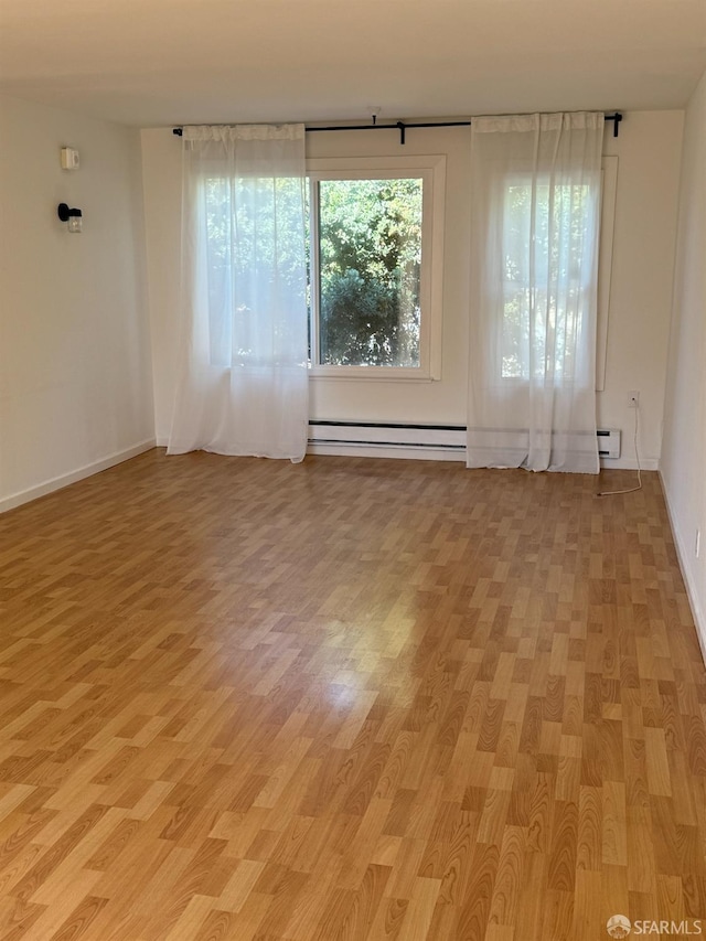 unfurnished room featuring light hardwood / wood-style flooring and a baseboard heating unit