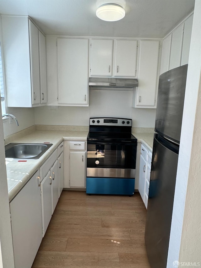 kitchen with fridge, sink, electric range, and white cabinetry