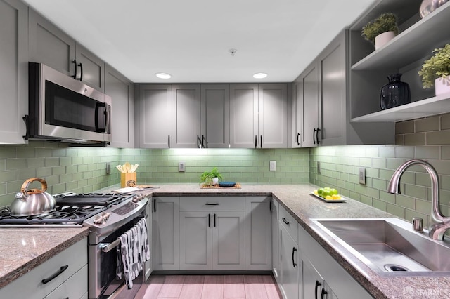 kitchen with backsplash, gray cabinets, sink, and appliances with stainless steel finishes