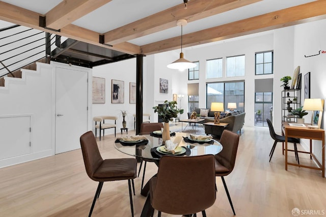 dining space with beamed ceiling and light hardwood / wood-style floors