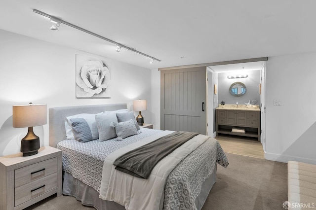 bedroom featuring ensuite bathroom, light colored carpet, and track lighting