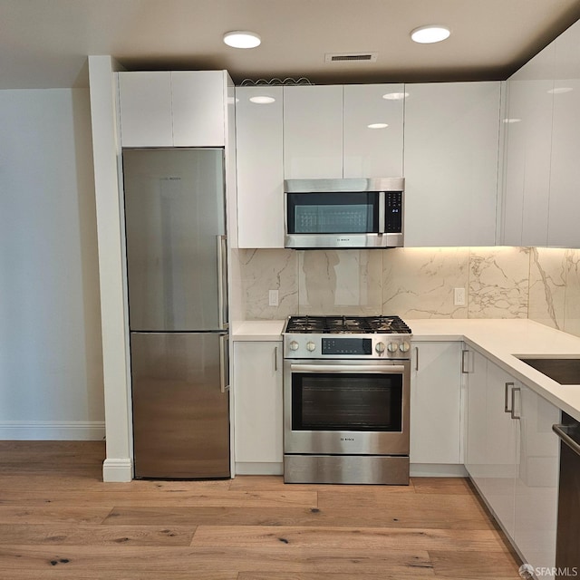 kitchen with light hardwood / wood-style floors, white cabinetry, and stainless steel appliances