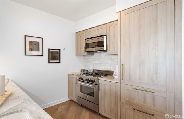 401 Harrison St Unit 25F, San Francisco, CA 94105 - kitchen with appliances with stainless steel finishes, light brown cabinets, backsplash, light wood-type flooring, and baseboards