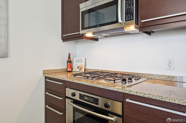 kitchen with dark brown cabinetry, light stone counters, and stainless steel appliances