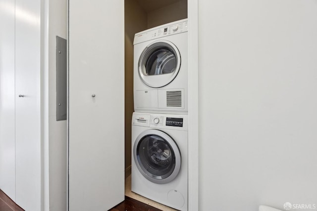 clothes washing area with stacked washing maching and dryer