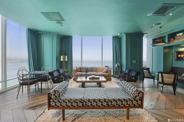 living room featuring hardwood / wood-style floors, a wall of windows, and a water view