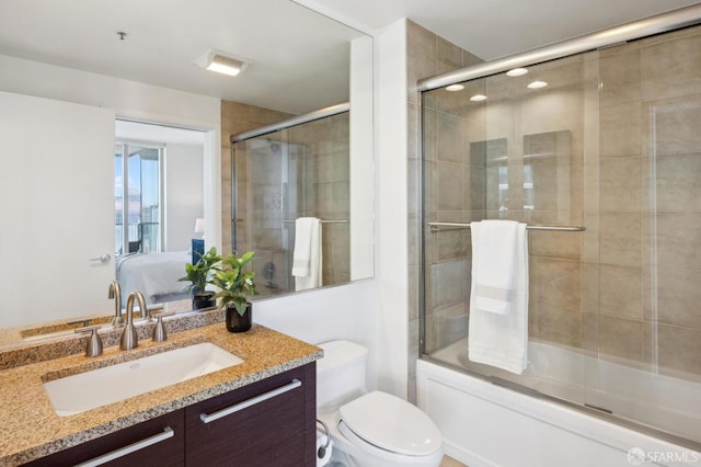 full bathroom with toilet, vanity, and bath / shower combo with glass door