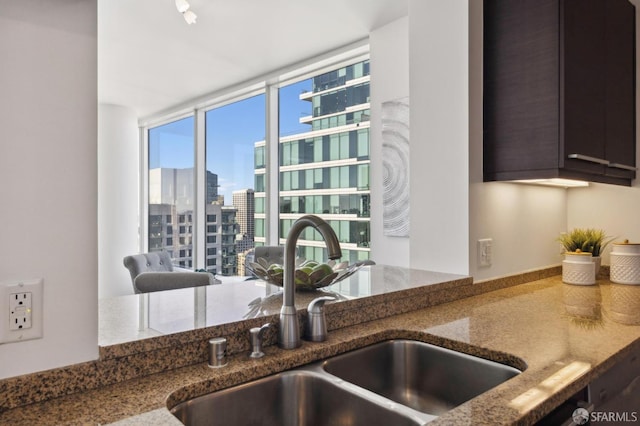 kitchen featuring dark stone countertops, sink, and expansive windows