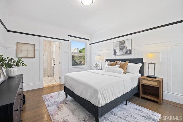 bedroom with wood finished floors and a decorative wall