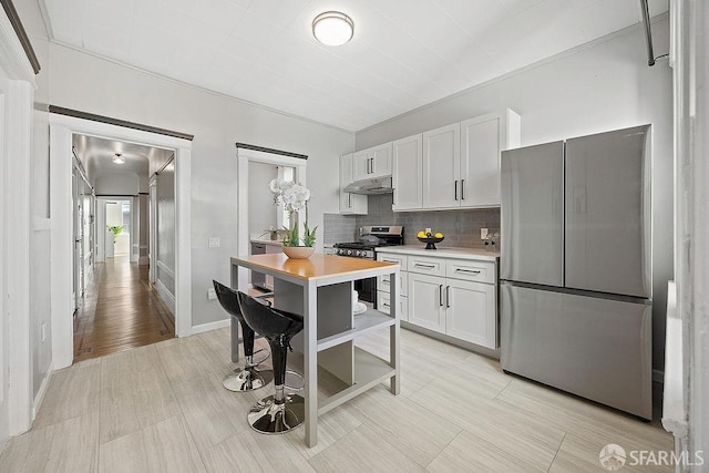 kitchen featuring decorative backsplash, stainless steel appliances, light countertops, under cabinet range hood, and white cabinetry