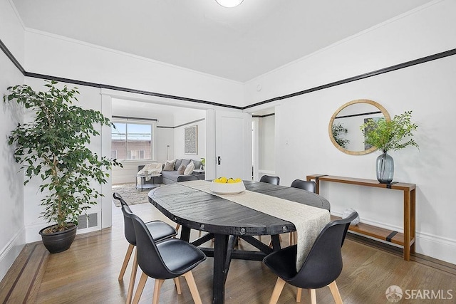 dining room with ornamental molding, wood finished floors, visible vents, and baseboards