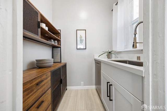 interior space featuring open shelves, light countertops, a sink, dishwasher, and baseboards