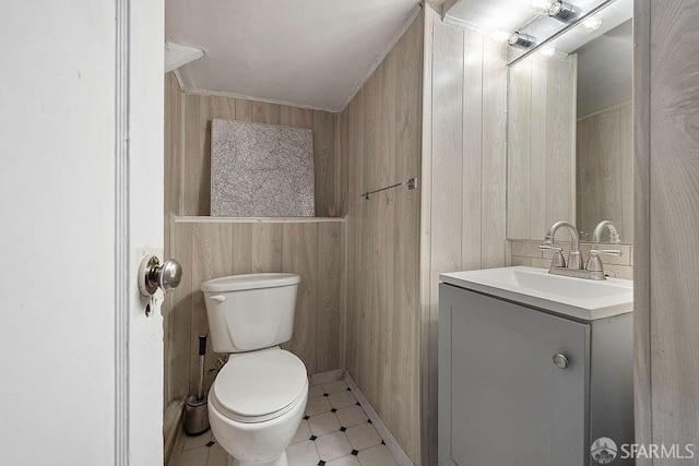 half bath with toilet, vanity, and tile patterned floors