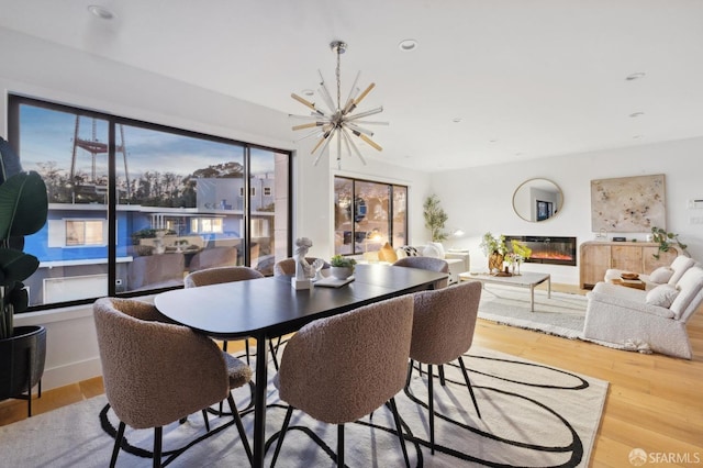 dining space with a healthy amount of sunlight, a chandelier, and light wood-type flooring