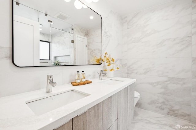 bathroom featuring vanity, toilet, and tile walls