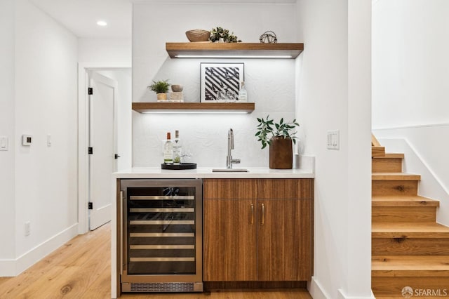 bar featuring wine cooler, sink, and light wood-type flooring