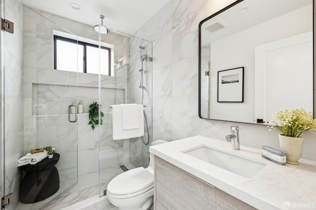 bathroom featuring vanity, toilet, a shower with door, and tile walls