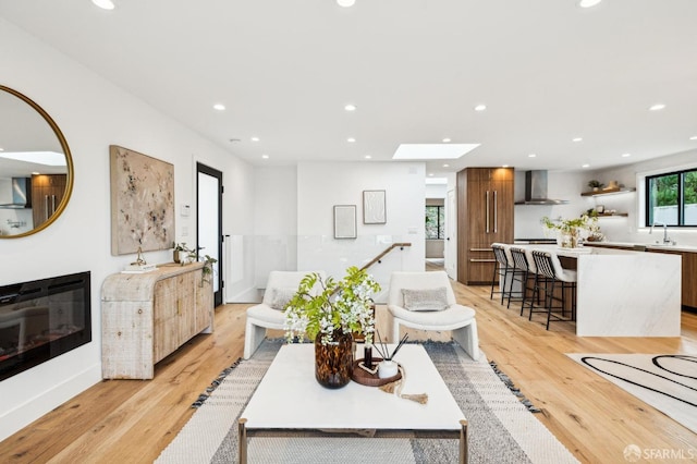 living room with sink, a skylight, and light hardwood / wood-style floors