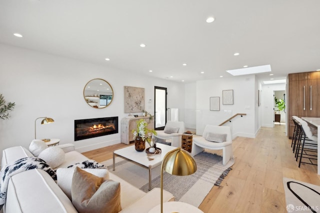 living room featuring a skylight and light hardwood / wood-style floors