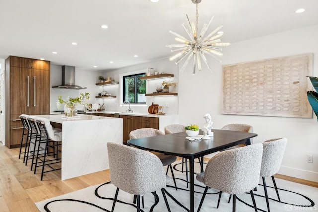 dining area with sink, light hardwood / wood-style floors, and a chandelier