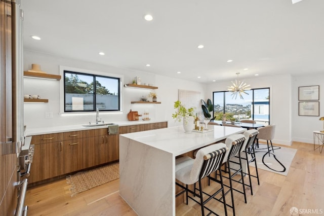 kitchen with a kitchen island, sink, light hardwood / wood-style floors, and plenty of natural light