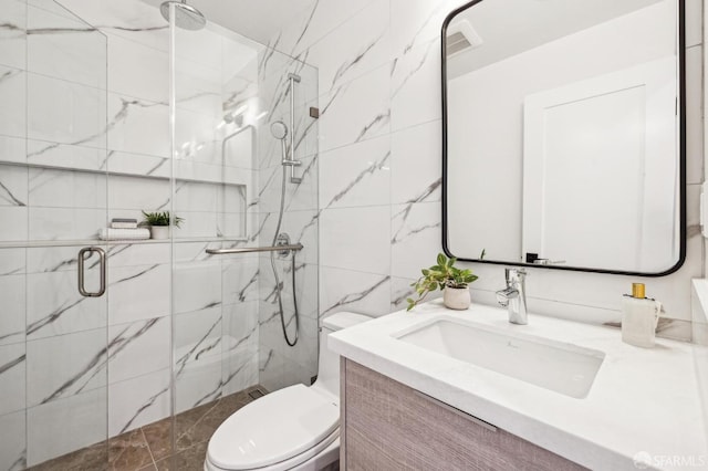 bathroom featuring vanity, a shower with door, tile walls, and toilet