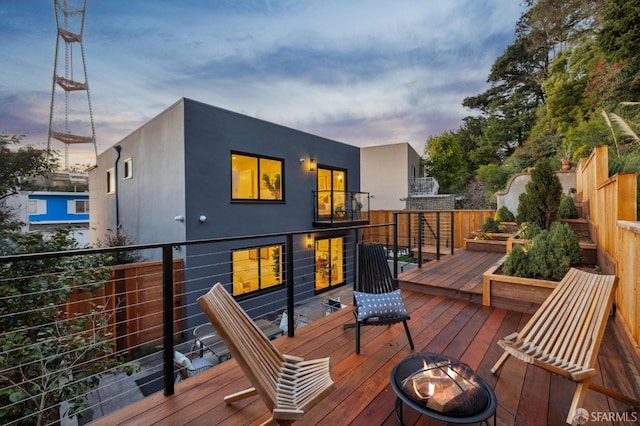 deck at dusk featuring an outdoor fire pit