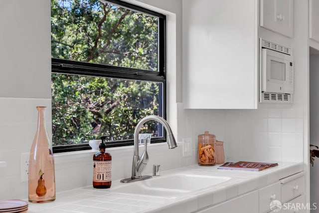 35 Ardilla Rd, Orinda, CA 94563 - kitchen featuring white microwave, white cabinets, tile countertops, and decorative backsplash