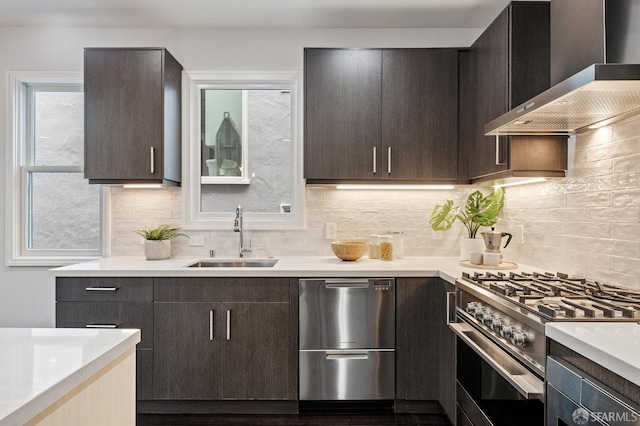 kitchen featuring sink, high end range, dark brown cabinets, dishwasher, and wall chimney range hood