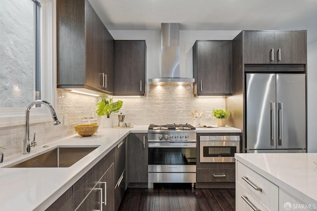 kitchen with sink, white cabinetry, wall chimney range hood, stainless steel appliances, and backsplash