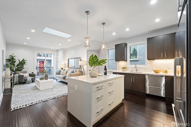 kitchen with sink, a skylight, a center island, dark hardwood / wood-style flooring, and stainless steel appliances