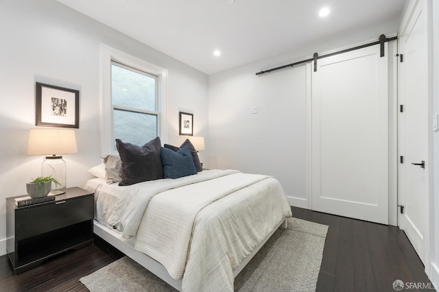 bedroom featuring dark hardwood / wood-style flooring and a barn door