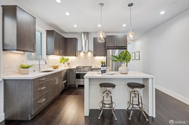 kitchen with sink, a center island, stainless steel appliances, dark wood-type flooring, and wall chimney exhaust hood