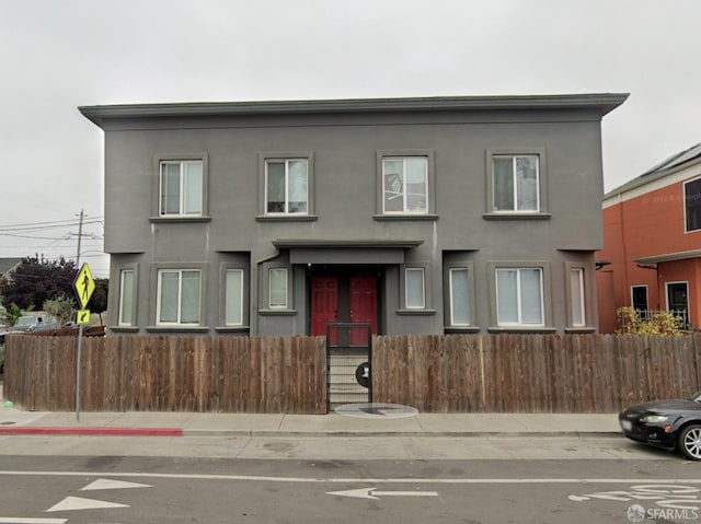 multi unit property featuring a fenced front yard and stucco siding