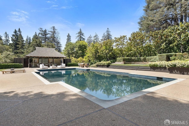 pool with an outbuilding, a patio area, fence, and an exterior structure