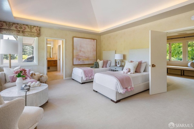 carpeted bedroom featuring connected bathroom and a raised ceiling