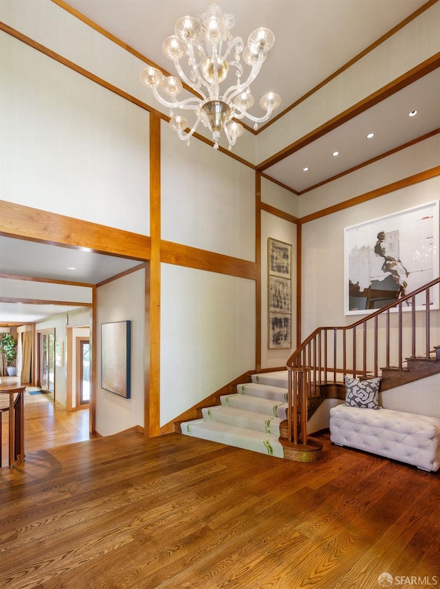 stairs featuring ornamental molding, recessed lighting, a notable chandelier, and wood finished floors