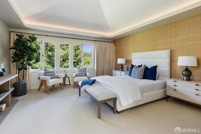 bedroom with a raised ceiling and light carpet