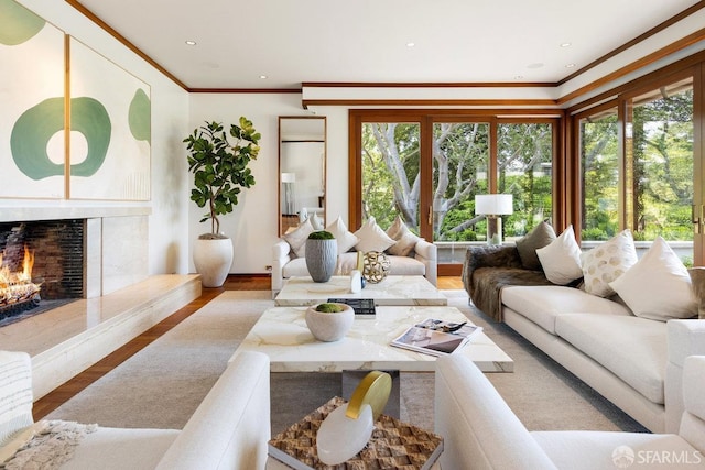 living area with recessed lighting, a high end fireplace, ornamental molding, and wood finished floors