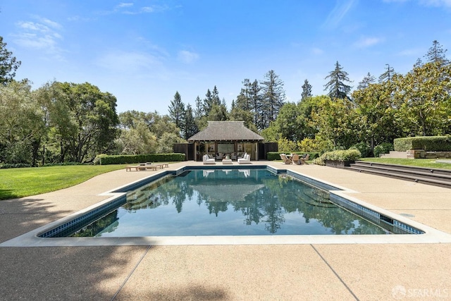 outdoor pool with an outbuilding, a patio, and an exterior structure