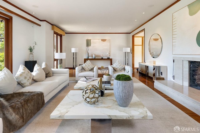 living area with a premium fireplace, wood finished floors, ornamental molding, and recessed lighting