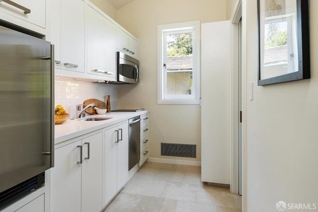 kitchen with visible vents, appliances with stainless steel finishes, light countertops, a sink, and decorative backsplash