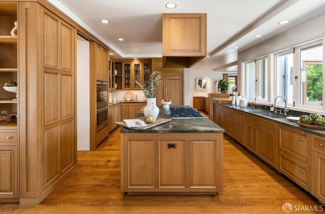 kitchen with plenty of natural light, a kitchen island, dark countertops, appliances with stainless steel finishes, and a sink